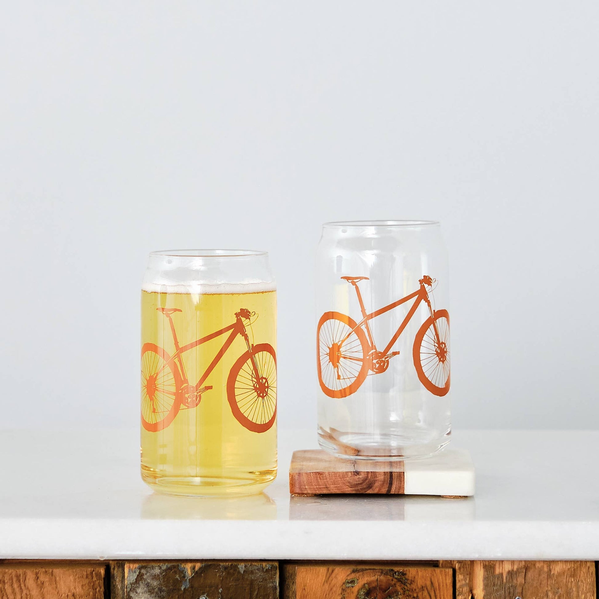 Two glasses with bicycle designs on a white surface.