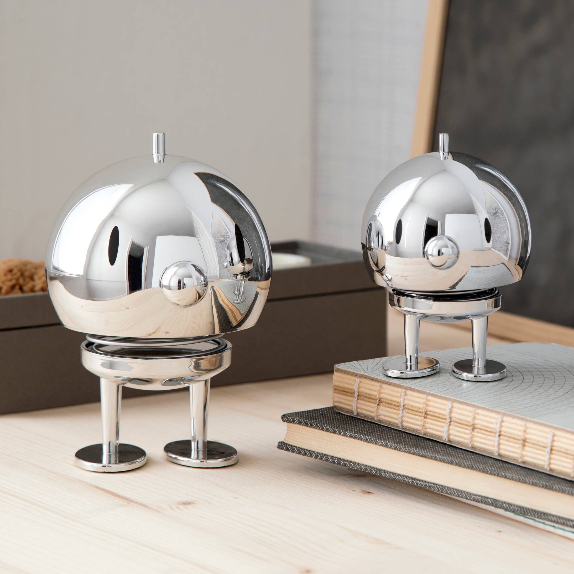 Two metallic sculptures on a wooden surface with a blurred background