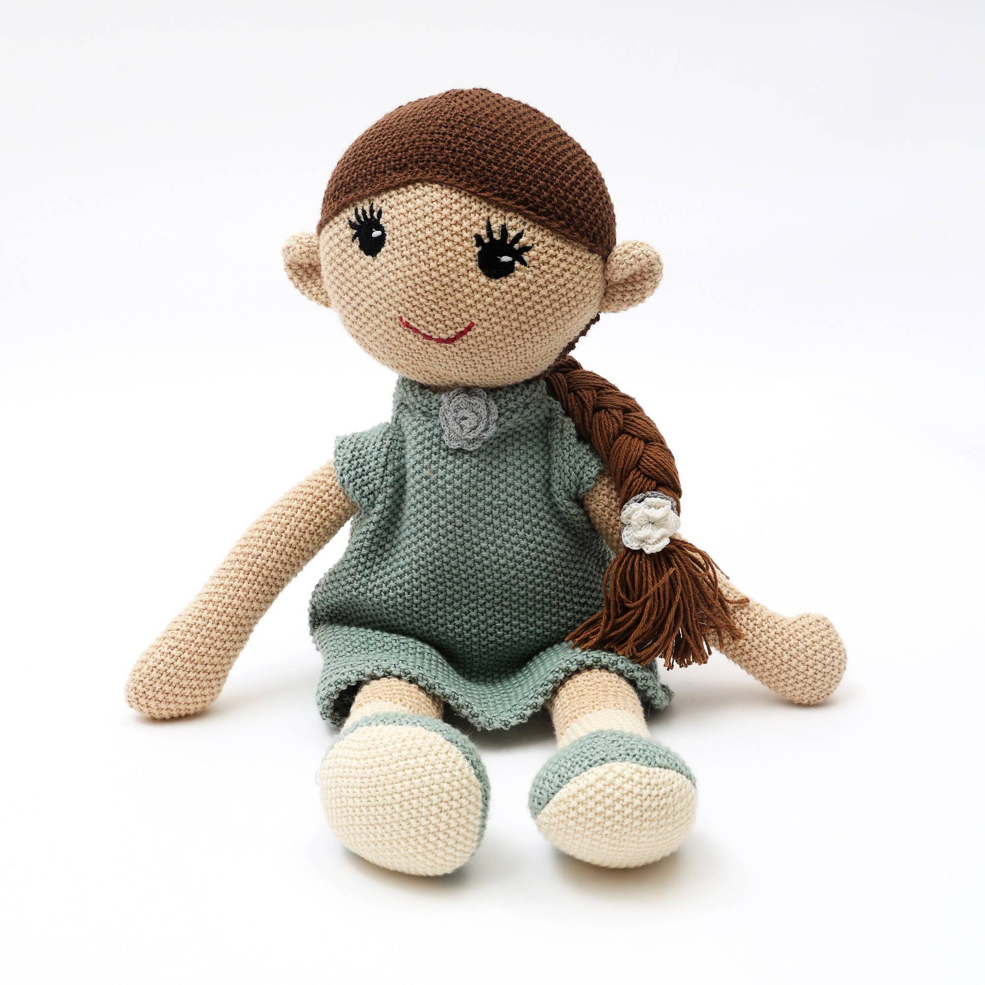 Knitted doll with brown hair and green dress on a white background