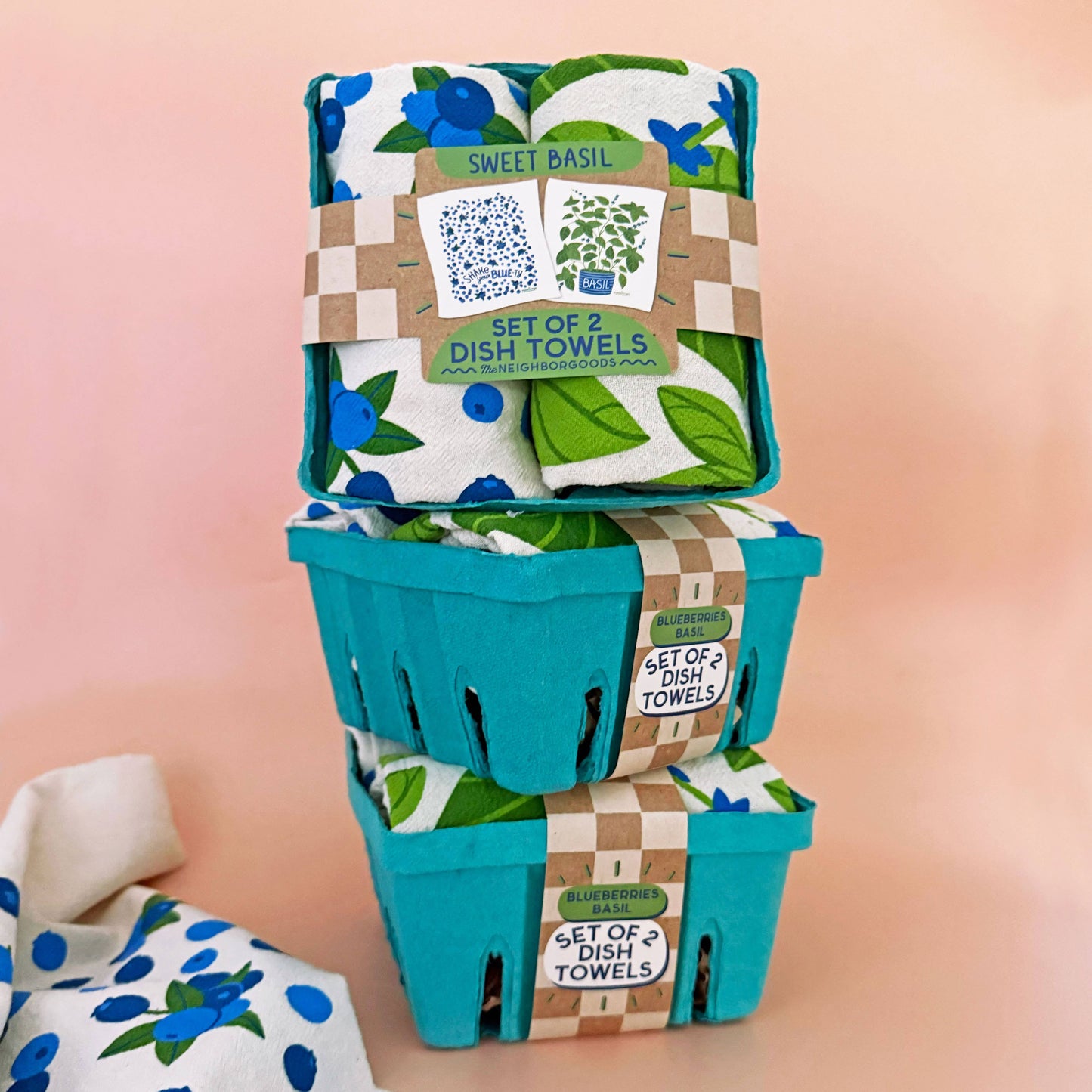 Set of dish towels in a teal packaging with a pink background