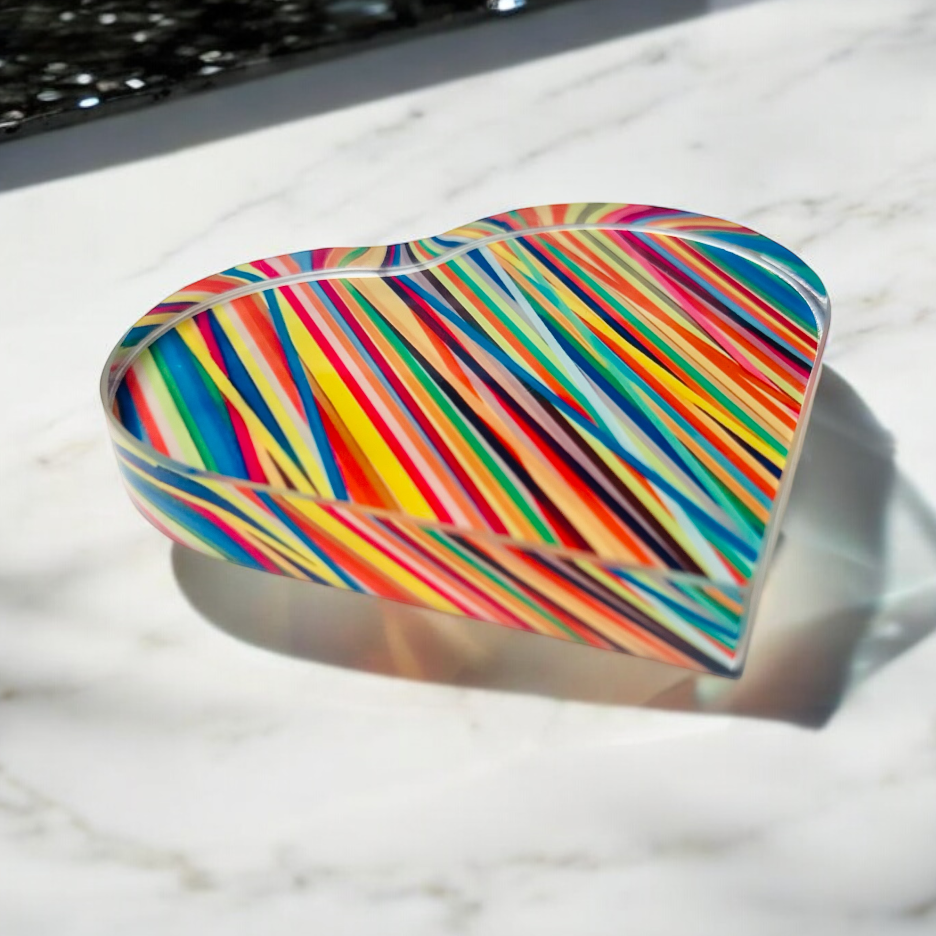 Colorful striped heart-shaped object on a marble surface