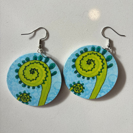 Pair of earrings with fiddlehead design on blue background