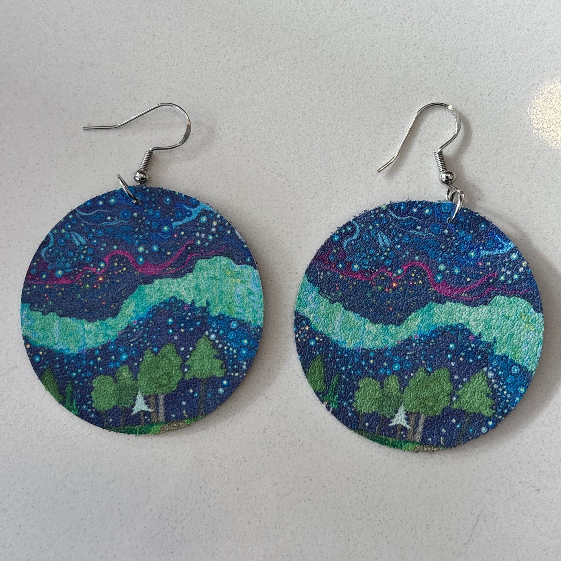 Round earrings with nature-themed design on a white background