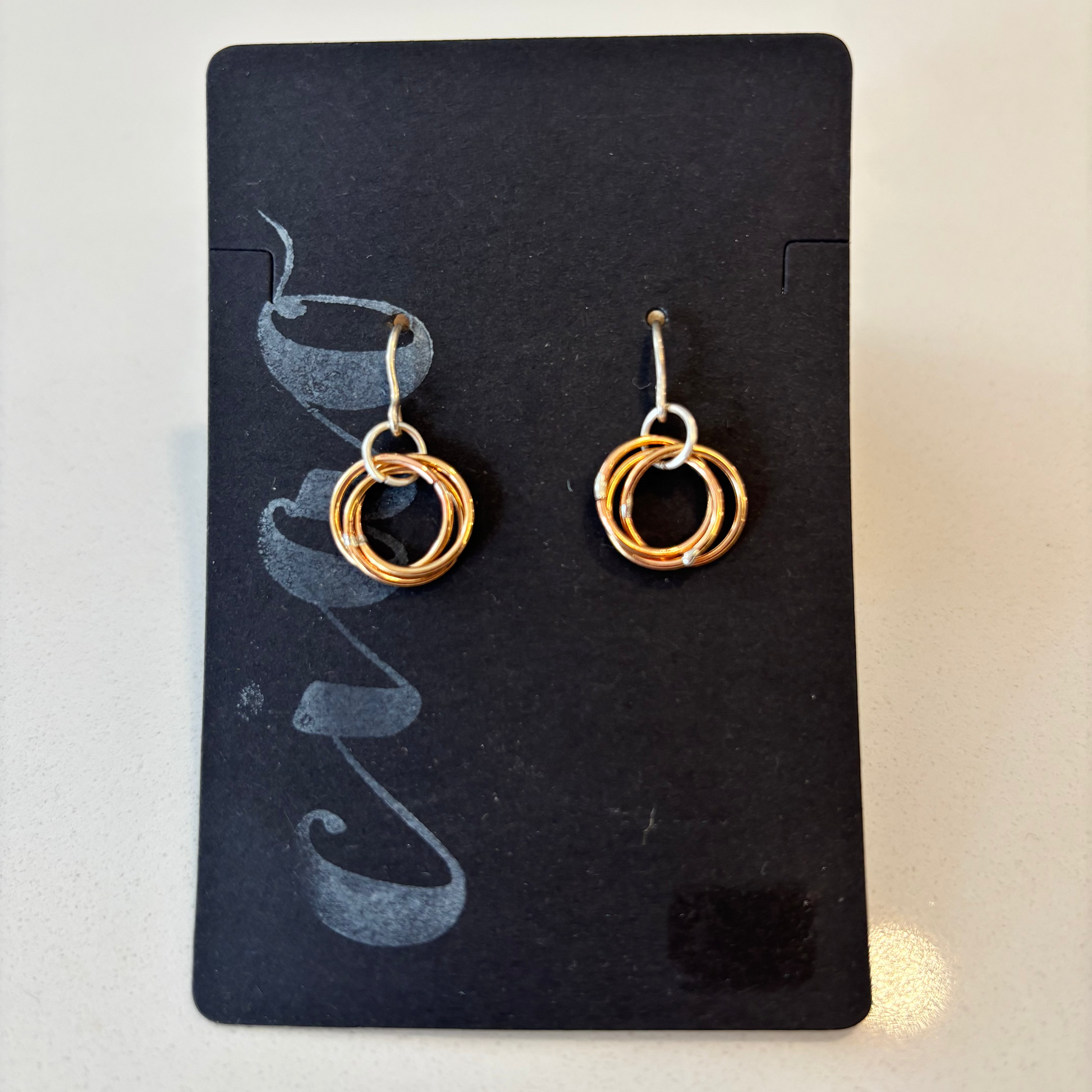 Pair of gold hoop earrings on a black card with a white background
