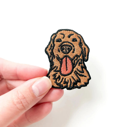 Hand holding a dog-shaped patch with a white background
