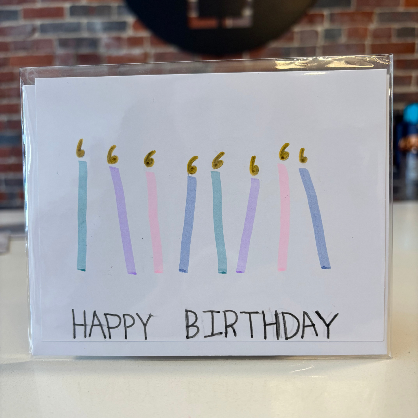 Birthday card with colorful candles and 'Happy Birthday' text on a white surface.