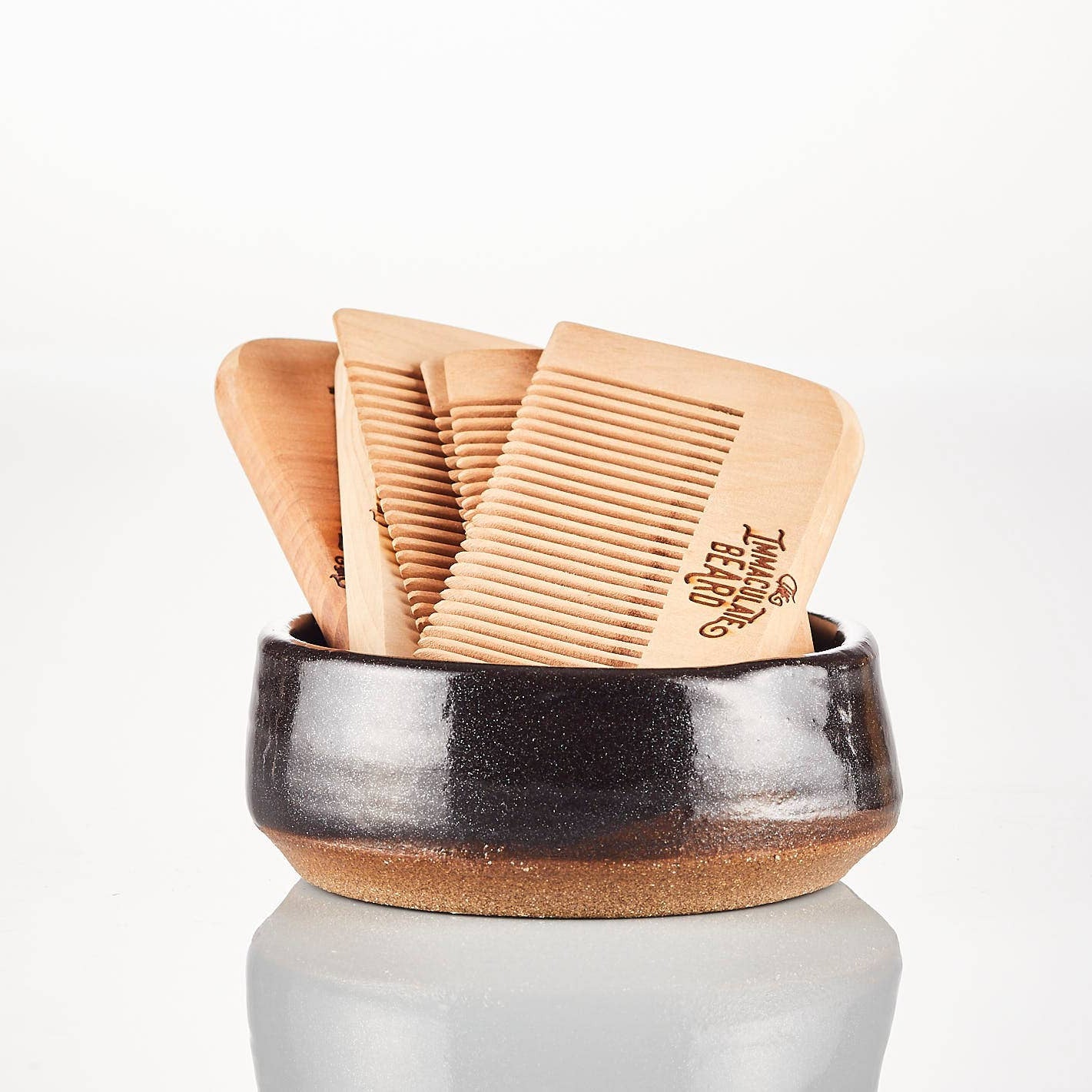 Set of wooden combs in a black ceramic holder on a white background