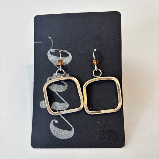 Pair of square earrings on a black card with silver and gold accents.