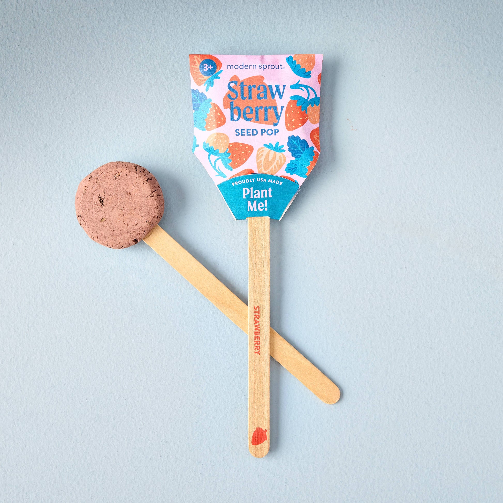 Strawberry seed pop with a wooden stick and packaging on a light blue background