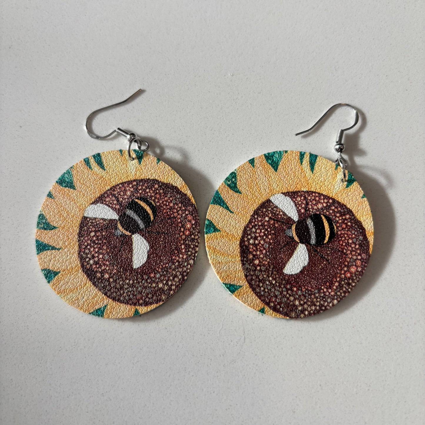 Pair of earrings with sunflower design on a gray background