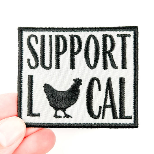 Patch with 'Support Local' text and a chicken silhouette held by a hand on a white background