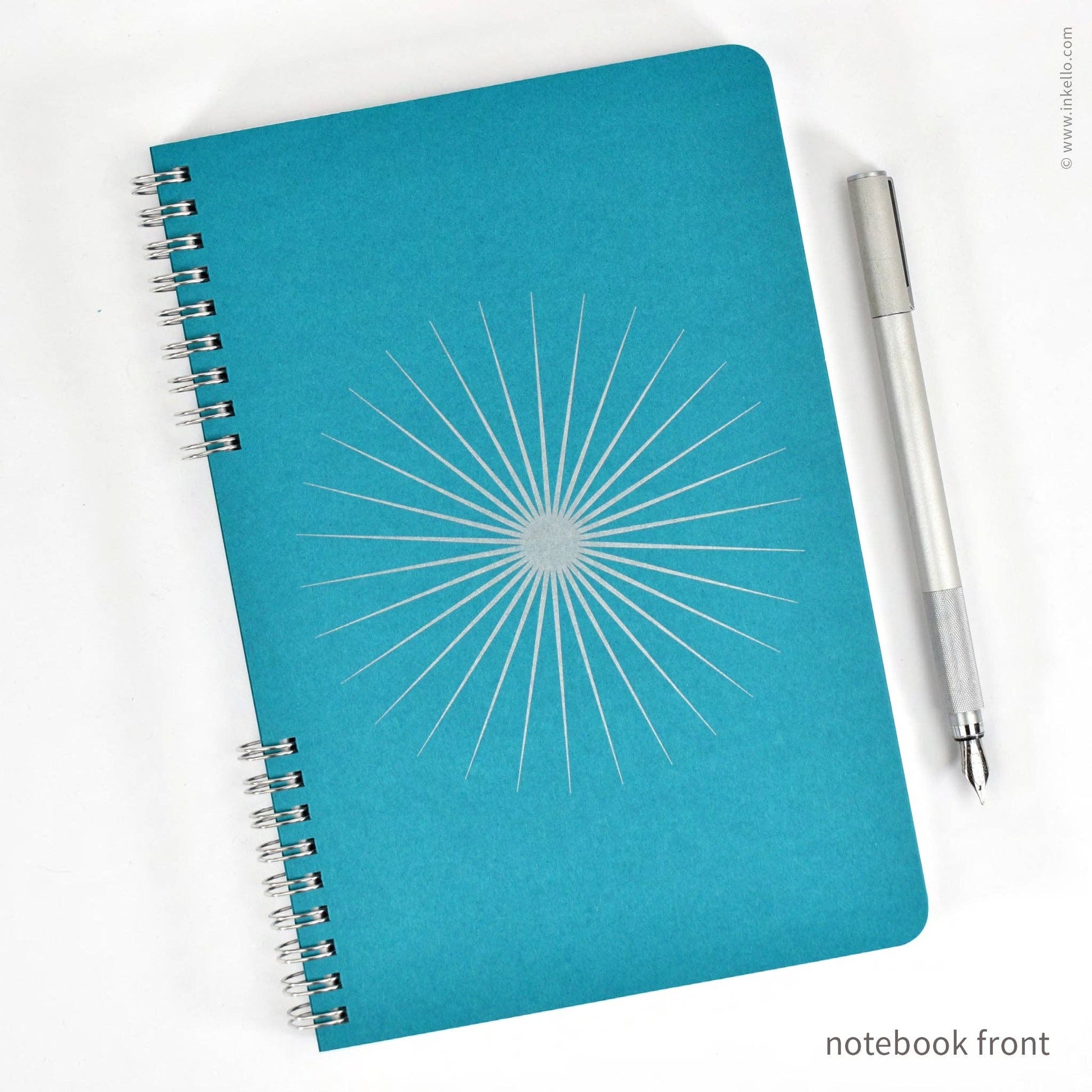 Blue notebook with starburst design and a pen on a white background