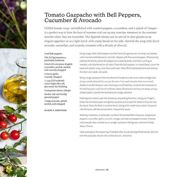 Tomato gazpacho with bell peppers, cucumber, and avocado served in glasses on a table with ingredients.