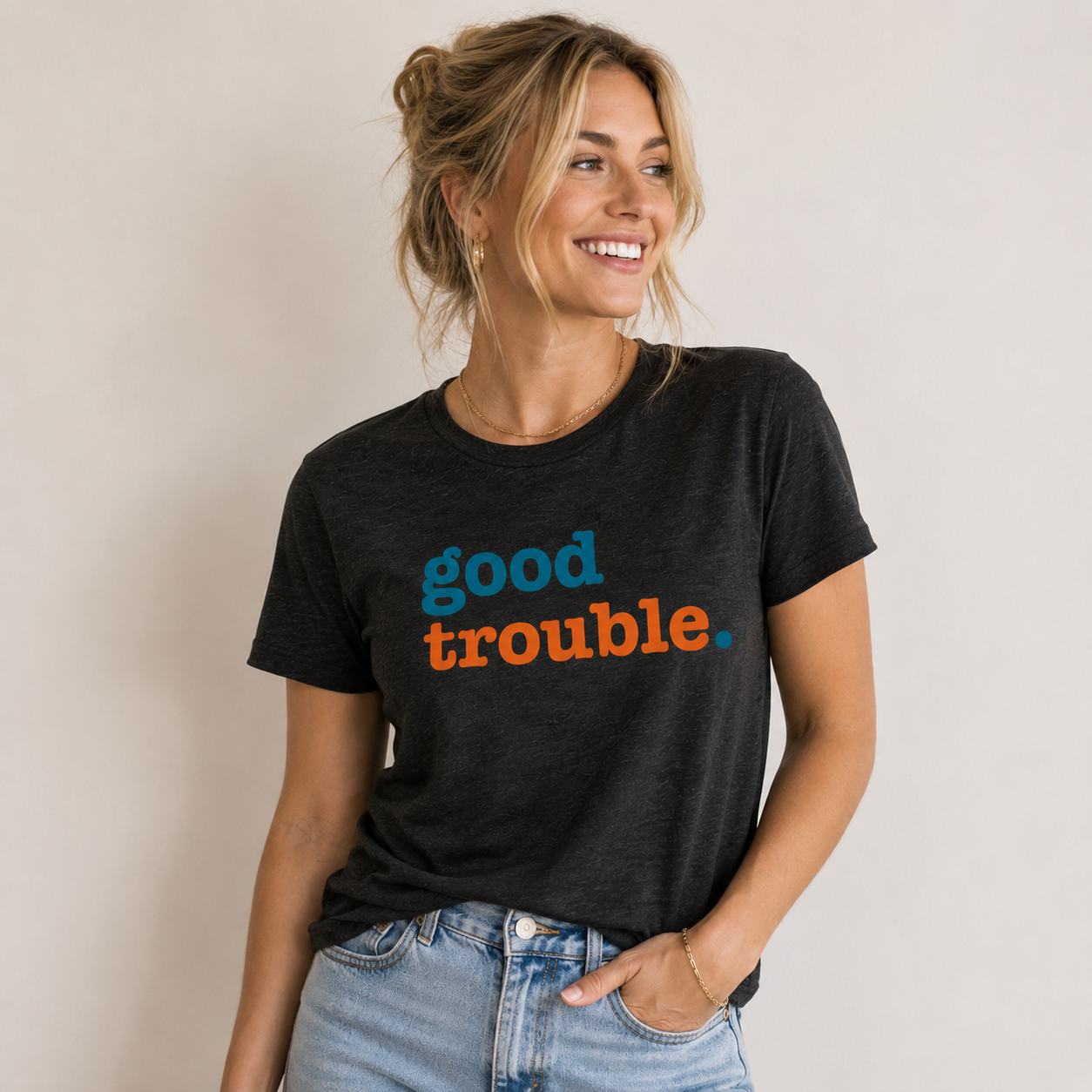 Woman wearing a black t-shirt with 'good trouble' text on a plain background
